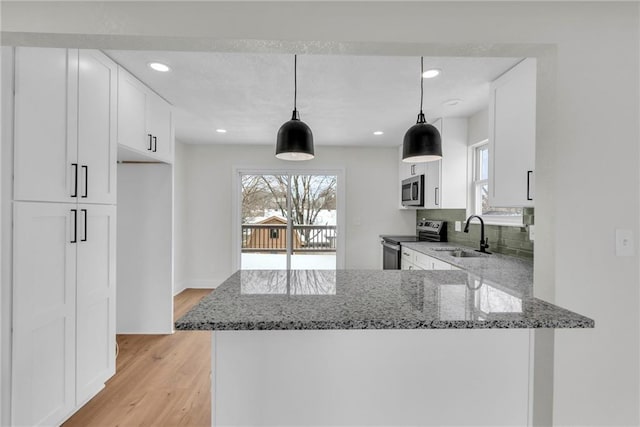 kitchen featuring white cabinets, light stone counters, stainless steel appliances, and a sink