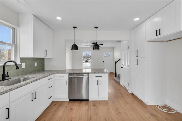 kitchen with white cabinets, a sink, light wood-style flooring, and stainless steel dishwasher