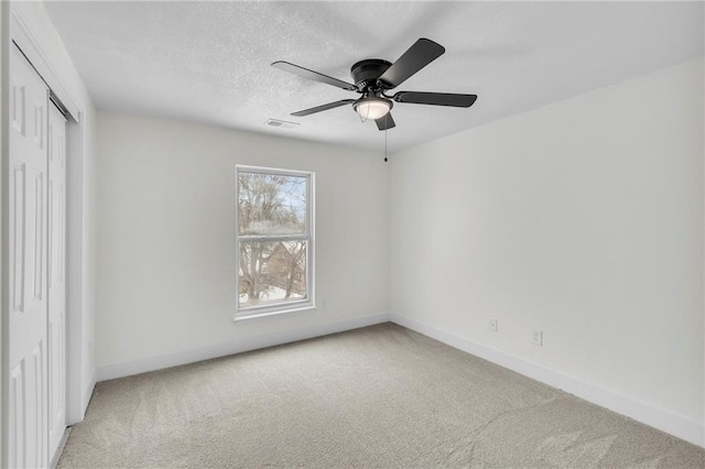 unfurnished bedroom featuring a textured ceiling, a closet, baseboards, and light colored carpet