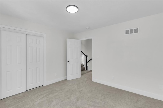 unfurnished bedroom with carpet, a closet, visible vents, and baseboards