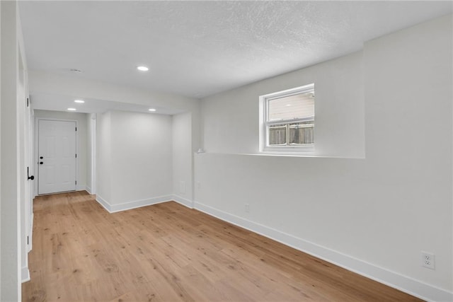 spare room featuring a textured ceiling, recessed lighting, wood finished floors, and baseboards