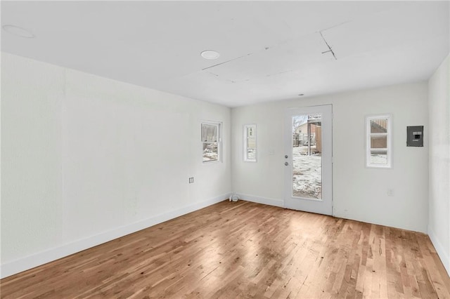 spare room featuring hardwood / wood-style floors, electric panel, and baseboards