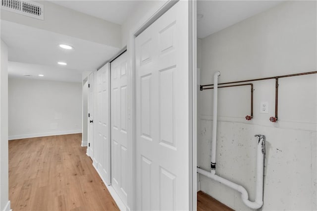 hall with light wood-style floors, recessed lighting, visible vents, and baseboards