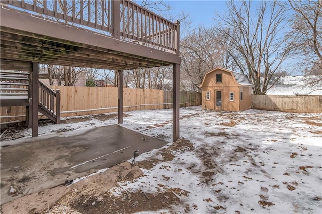 snowy yard with a patio area, a fenced backyard, and an outdoor structure