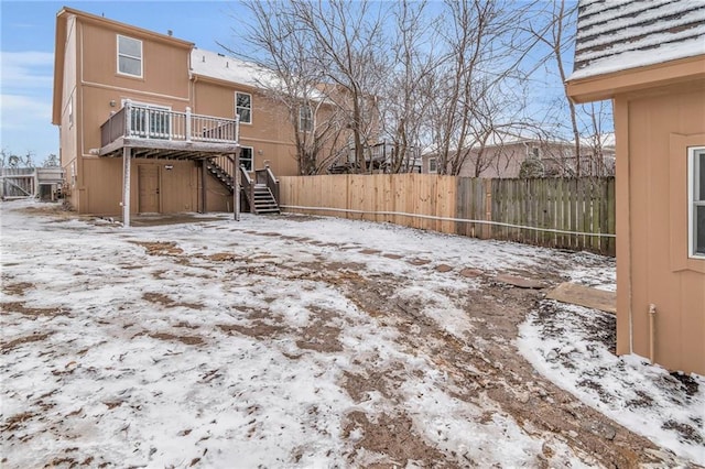 snow covered property featuring stairway, fence, and a wooden deck