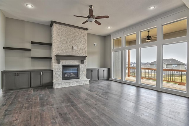 unfurnished living room featuring dark wood-style floors, recessed lighting, visible vents, a ceiling fan, and a stone fireplace