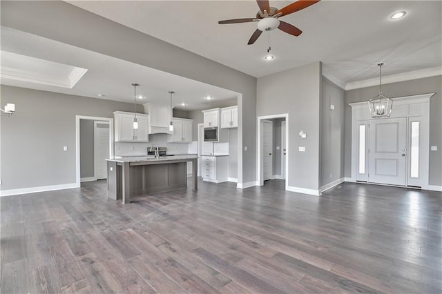 kitchen featuring light countertops, open floor plan, decorative light fixtures, and an island with sink