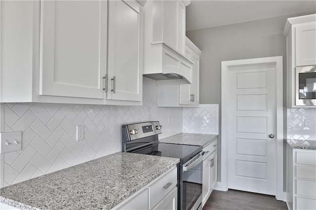 kitchen with light stone counters, stainless steel electric stove, white cabinetry, decorative backsplash, and built in microwave