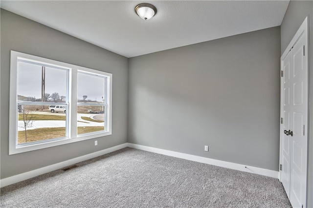 spare room with baseboards, visible vents, and light colored carpet