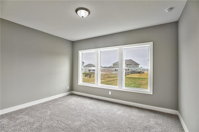 carpeted spare room featuring baseboards