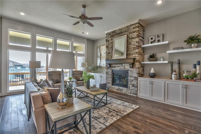 living area with dark wood-style floors, recessed lighting, ceiling fan, and a stone fireplace