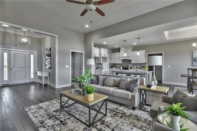 living area featuring dark wood-style floors, ceiling fan with notable chandelier, recessed lighting, and baseboards