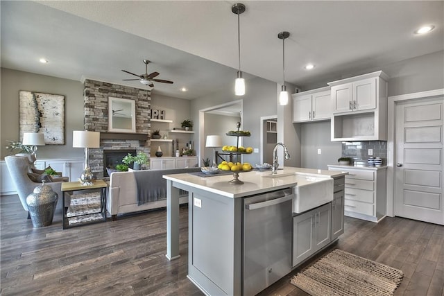 kitchen with light countertops, open floor plan, a kitchen island with sink, white cabinets, and dishwasher