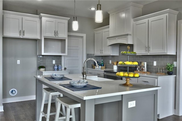 kitchen featuring a kitchen island with sink, light countertops, hanging light fixtures, and white cabinetry