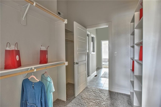 walk in closet with light tile patterned floors, visible vents, and light colored carpet