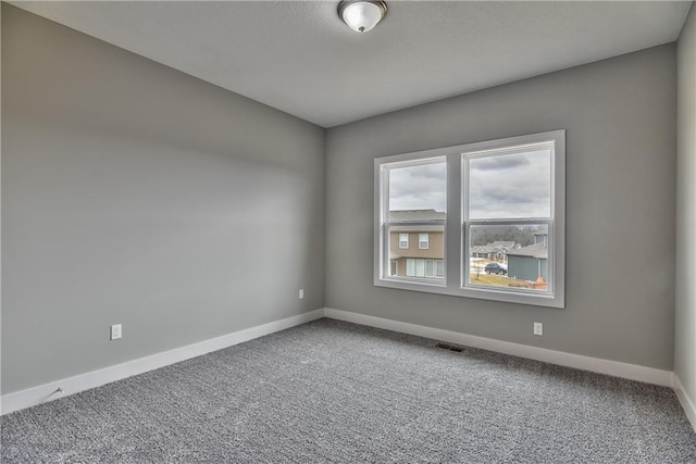 carpeted spare room with visible vents and baseboards