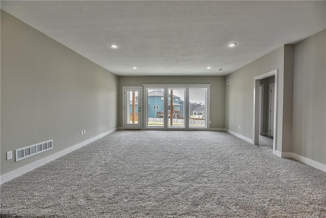 empty room featuring carpet floors, visible vents, a textured ceiling, and baseboards