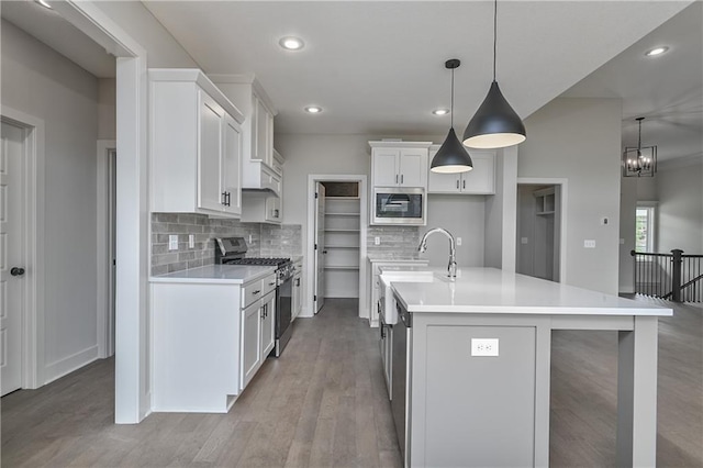 2850 W Wabash St, Olathe, KS 66061 - kitchen with appliances with stainless steel finishes, tasteful backsplash, light countertops, a center island with sink, and white cabinetry