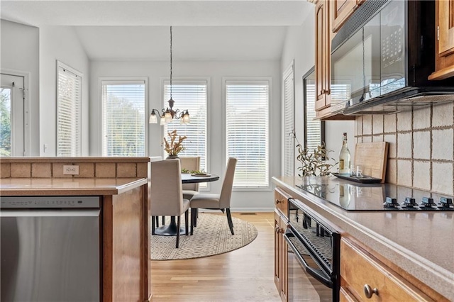 dining room with lofted ceiling, light wood finished floors, a wealth of natural light, and a notable chandelier