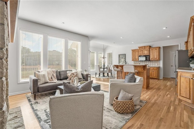 living room with baseboards, recessed lighting, a wealth of natural light, and light wood-style floors