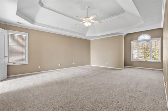 spare room featuring light carpet, a tray ceiling, and baseboards