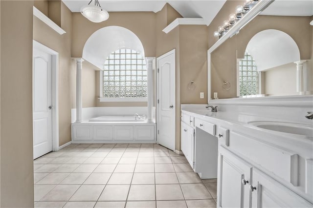 bathroom featuring double vanity, decorative columns, tile patterned floors, a garden tub, and a sink