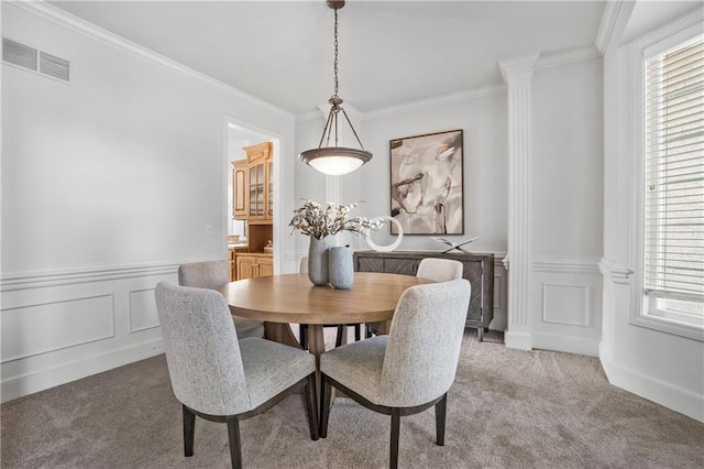 dining area featuring visible vents, wainscoting, crown molding, carpet flooring, and a decorative wall