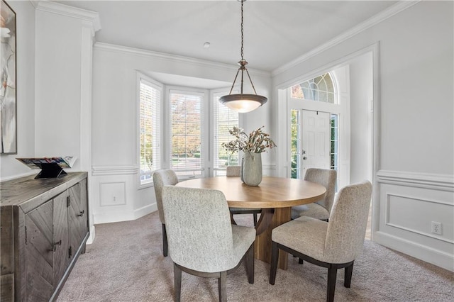 dining room with ornamental molding, a decorative wall, and light colored carpet