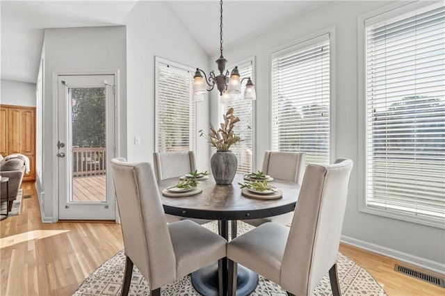 dining room featuring visible vents, vaulted ceiling, light wood-style flooring, and an inviting chandelier