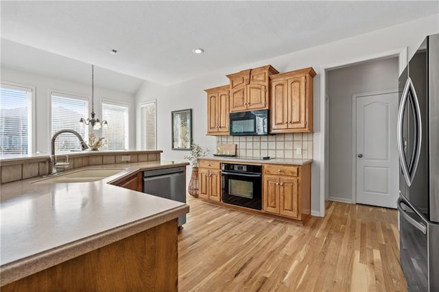 kitchen with light countertops, hanging light fixtures, an inviting chandelier, a sink, and black appliances