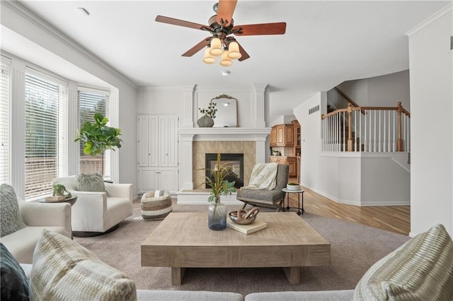 living room with crown molding, a fireplace, light wood-style flooring, baseboards, and stairs