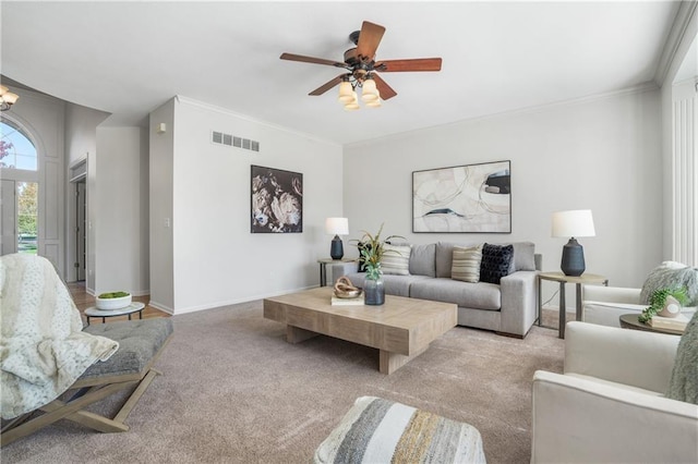 living area featuring baseboards, visible vents, light colored carpet, crown molding, and ceiling fan with notable chandelier