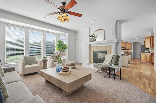 living area with ornamental molding, a high end fireplace, plenty of natural light, and light wood-style flooring