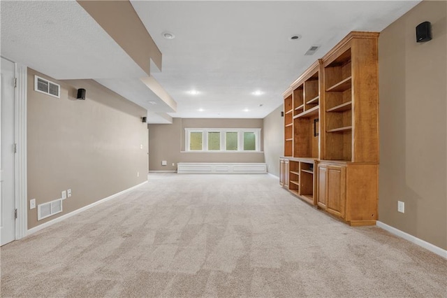 unfurnished living room with baseboards, visible vents, and light colored carpet