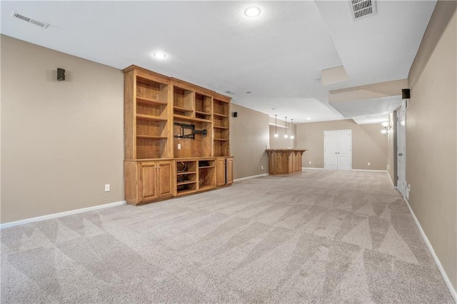 unfurnished living room featuring baseboards, visible vents, and light colored carpet