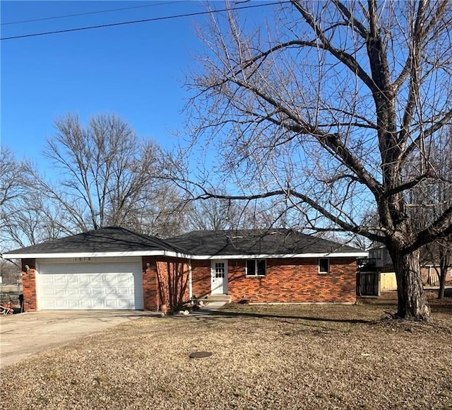 ranch-style home featuring an attached garage, concrete driveway, and brick siding