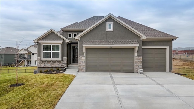 craftsman-style house with an attached garage, fence, driveway, stucco siding, and a front lawn