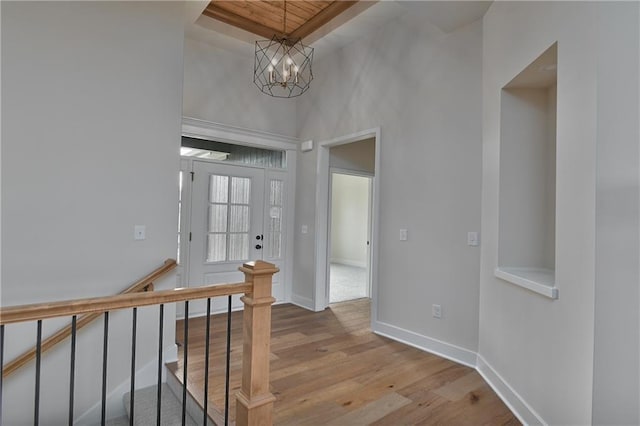 entrance foyer with a chandelier, a towering ceiling, baseboards, and wood finished floors