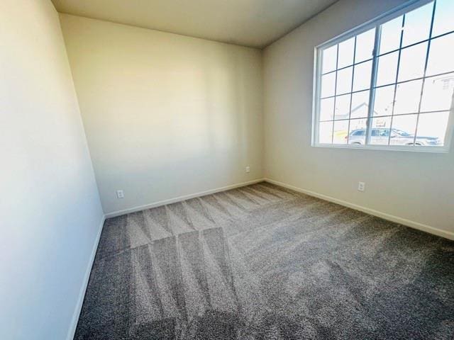 carpeted spare room featuring baseboards