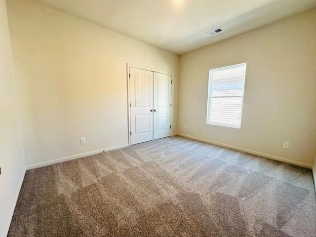 unfurnished bedroom with a closet, carpet, visible vents, and baseboards