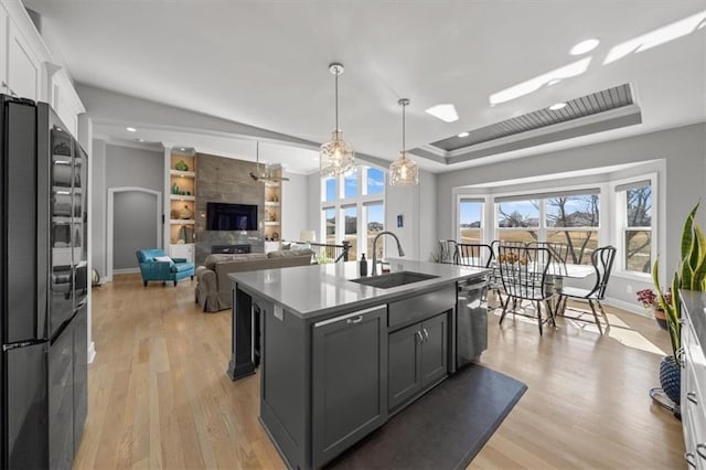 kitchen featuring light wood finished floors, a raised ceiling, freestanding refrigerator, a sink, and stainless steel dishwasher