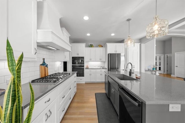 kitchen with premium range hood, appliances with stainless steel finishes, a sink, and white cabinets