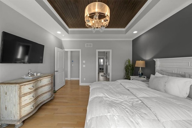 bedroom with light wood finished floors, visible vents, baseboards, an inviting chandelier, and a tray ceiling