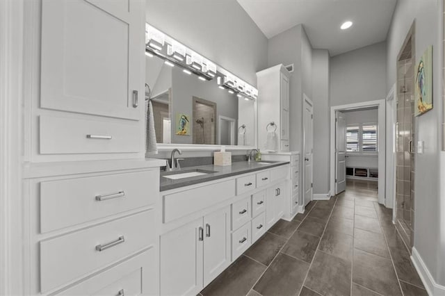 bathroom featuring double vanity, a stall shower, a sink, tile patterned flooring, and baseboards