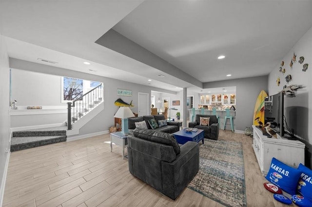 living area featuring light wood-style floors, stairs, and baseboards