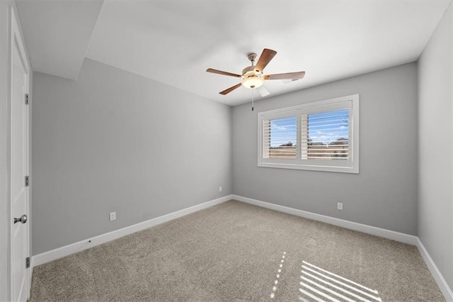 carpeted empty room with a ceiling fan and baseboards