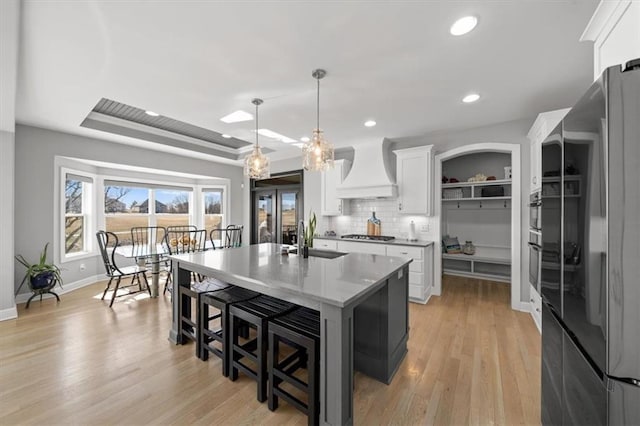 14423 N 145th St, Basehor, KS 66007 - kitchen featuring a kitchen island with sink, appliances with stainless steel finishes, a sink, white cabinets, and custom exhaust hood
