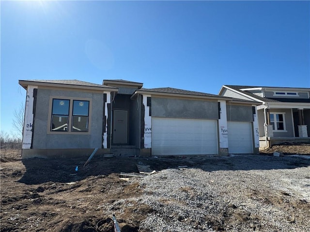 view of front of property with driveway, an attached garage, and stucco siding