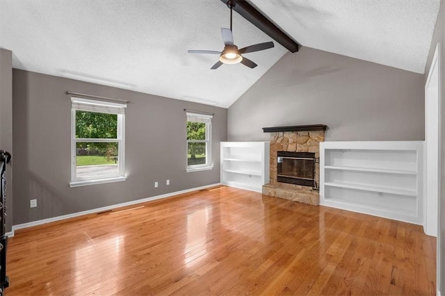 unfurnished living room featuring a fireplace, lofted ceiling with beams, a textured ceiling, wood finished floors, and baseboards