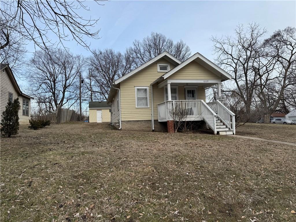 bungalow with a porch and an outbuilding